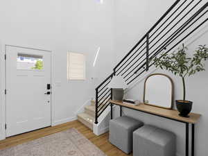 Foyer with light wood-style floors, baseboards, stairs, and a high ceiling