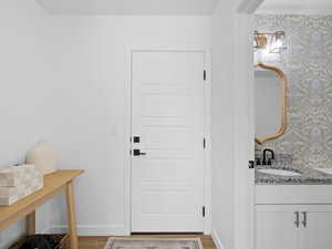 Doorway with a sink, baseboards, light wood finished floors, and wallpapered walls