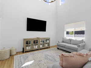 Living area featuring plenty of natural light, a high ceiling, and wood finished floors