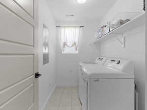 Laundry area with laundry area, visible vents, washer and dryer, baseboards, and light tile patterned floors