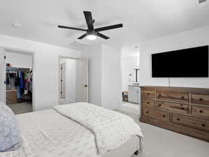 Bedroom featuring visible vents, a walk in closet, a closet, and light carpet
