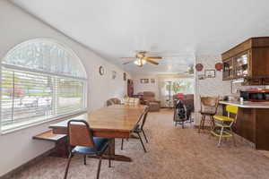 Dining space featuring a ceiling fan and light carpet