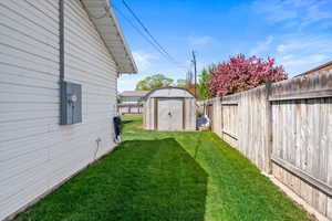View of yard with a storage shed, an outdoor structure, and a fenced backyard