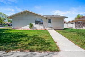 Rear view of house featuring a lawn and fence