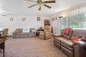 Carpeted living room with a ceiling fan