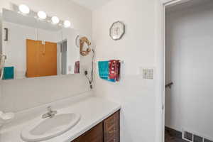 Bathroom with visible vents, vanity, and tile walls