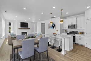 Dining room with light wood-style floors, recessed lighting, and a glass covered fireplace