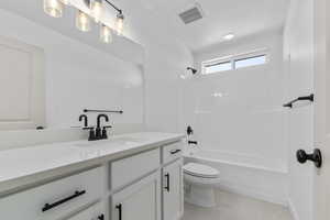 Bathroom featuring toilet, visible vents, washtub / shower combination, and vanity