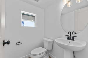 Bathroom with baseboards, a sink, visible vents, and toilet