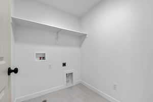 Laundry area with laundry area, light tile patterned flooring, baseboards, electric dryer hookup, and washer hookup