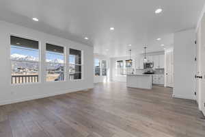 Unfurnished living room featuring recessed lighting, baseboards, a sink, and light wood-type flooring