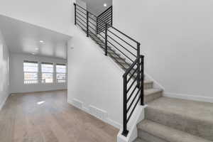 Stairs featuring wood-type flooring, recessed lighting, baseboards, and visible vents