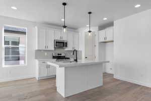 Kitchen with light countertops, white cabinetry, appliances with stainless steel finishes, and a sink