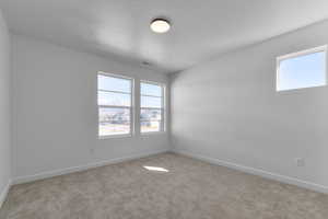 Unfurnished room featuring baseboards, carpet, a textured ceiling, and visible vents