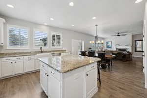 Kitchen featuring stainless steel dishwasher, a sink, ceiling fan, a kitchen island, and a fireplace