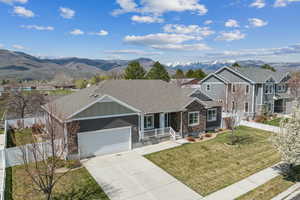 View of front of house with a front lawn, driveway, board and batten siding, and a mountain view