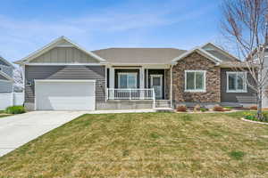 Craftsman-style home with a front yard, a garage, covered porch, driveway, and board and batten siding