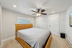 Bedroom featuring recessed lighting, a baseboard heating unit, light carpet, baseboards, and visible vents