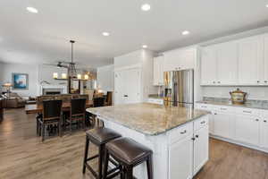 Kitchen featuring stainless steel refrigerator with ice dispenser, a ceiling fan, open floor plan, and light wood finished floors