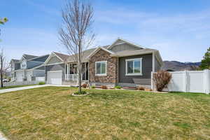 View of front of home with driveway, an attached garage, board and batten siding, and fence