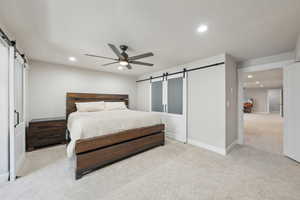Bedroom with a barn door, recessed lighting, and light carpet