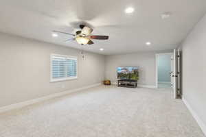 Carpeted living area featuring baseboards, recessed lighting, and a ceiling fan