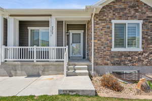 Entrance to property featuring covered porch and brick siding