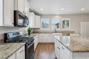 Kitchen with a sink, appliances with stainless steel finishes, a wealth of natural light, and white cabinetry