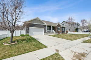 View of front of house with a front lawn, driveway, board and batten siding, an attached garage, and fence