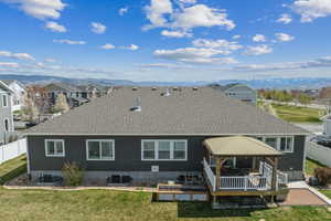 Back of property featuring fence, a gazebo, and a shingled roof