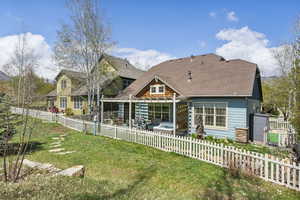 Back of property featuring a yard, a fenced backyard, roof with shingles, and a patio area