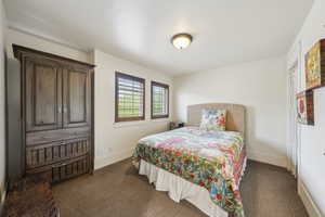 Bedroom featuring baseboards and dark carpet
