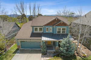 Craftsman-style house with a garage, a shingled roof, metal roof, a porch, and driveway