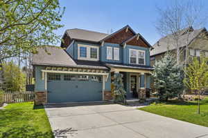 Craftsman inspired home featuring a garage, a front lawn, fence, covered porch, and driveway