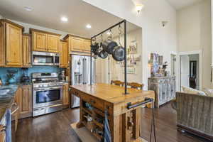 Kitchen featuring recessed lighting, appliances with stainless steel finishes, brown cabinetry, and dark wood-type flooring