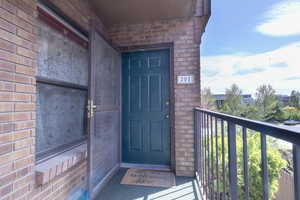 Doorway to property with a balcony and brick siding