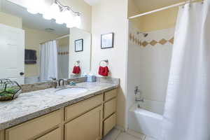 Bathroom with shower / tub combo with curtain, tile patterned flooring, and vanity