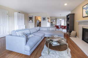Living room featuring wood finished floors, a tiled fireplace, and recessed lighting