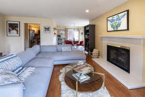 Living room with a tiled fireplace, visible vents, and wood finished floors