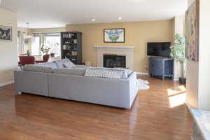 Living room with baseboards, light wood-type flooring, a fireplace, and recessed lighting
