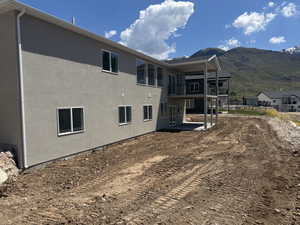 Back of property with a mountain view, stucco siding, a patio, and a balcony