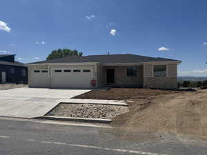 Ranch-style home featuring a garage, stone siding, roof with shingles, board and batten siding, and driveway