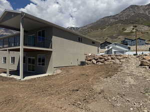 View of side of property with cooling unit, a mountain view, a balcony, a patio, and stucco siding