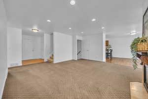 Living room with light colored carpet, recessed lighting, stairs, and visible vents