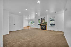 Unfurnished living room with recessed lighting, carpet flooring, baseboards, and a tiled fireplace
