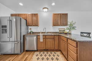Kitchen featuring a sink, appliances with stainless steel finishes, brown cabinetry, and a peninsula