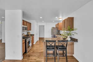 Kitchen with recessed lighting, brown cabinets, stainless steel appliances, and a kitchen bar