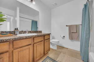 Bathroom with toilet, baseboards, a shower with curtain, and vanity