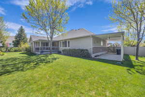 Back of property with a lawn, brick siding, fence, and a sunroom