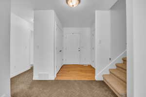 Entryway featuring stairway, baseboards, light carpet, and visible vents